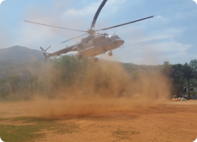 A helicoptor landing in a dusty field